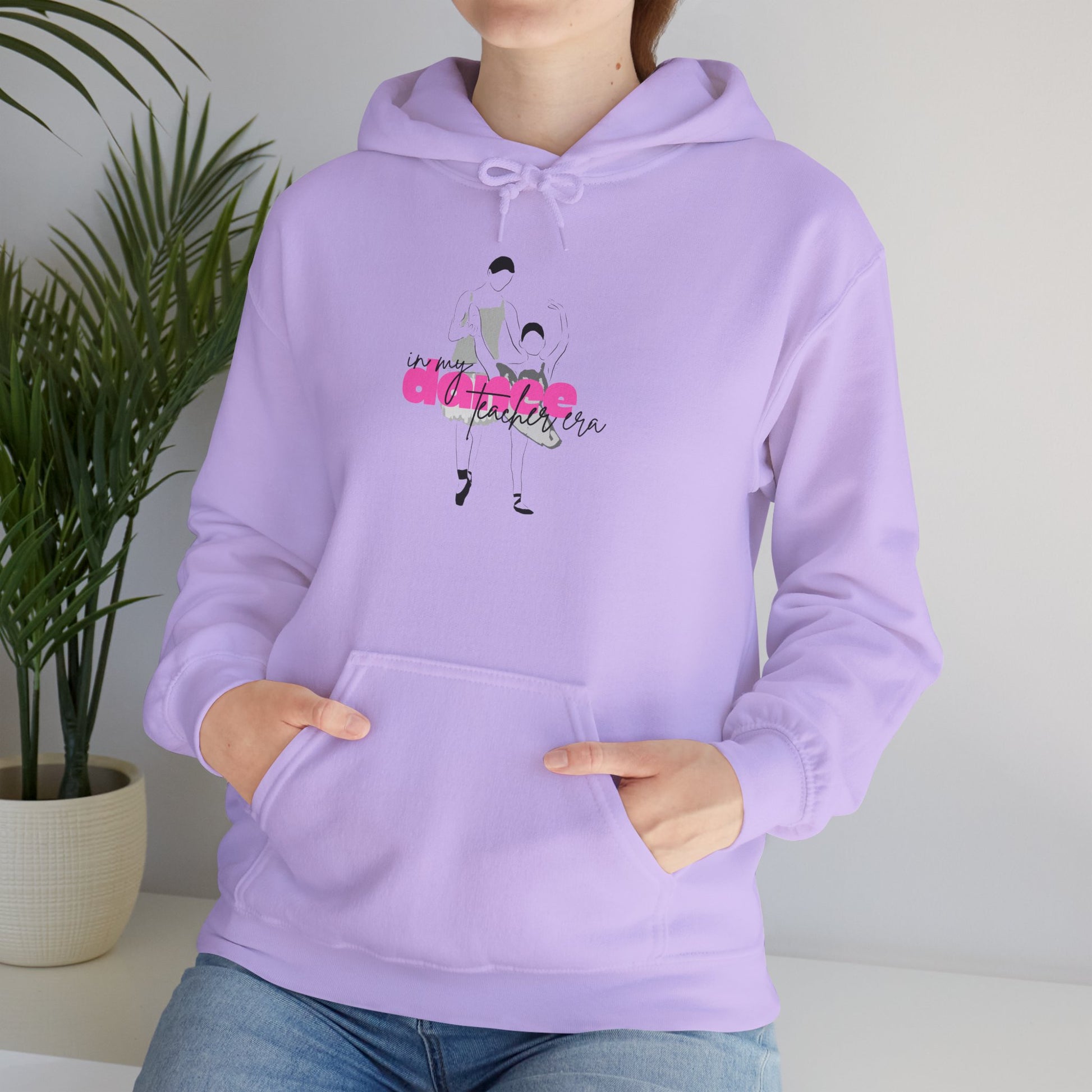 Person wearing a lavender hoodie with a graphic design on a neutral background