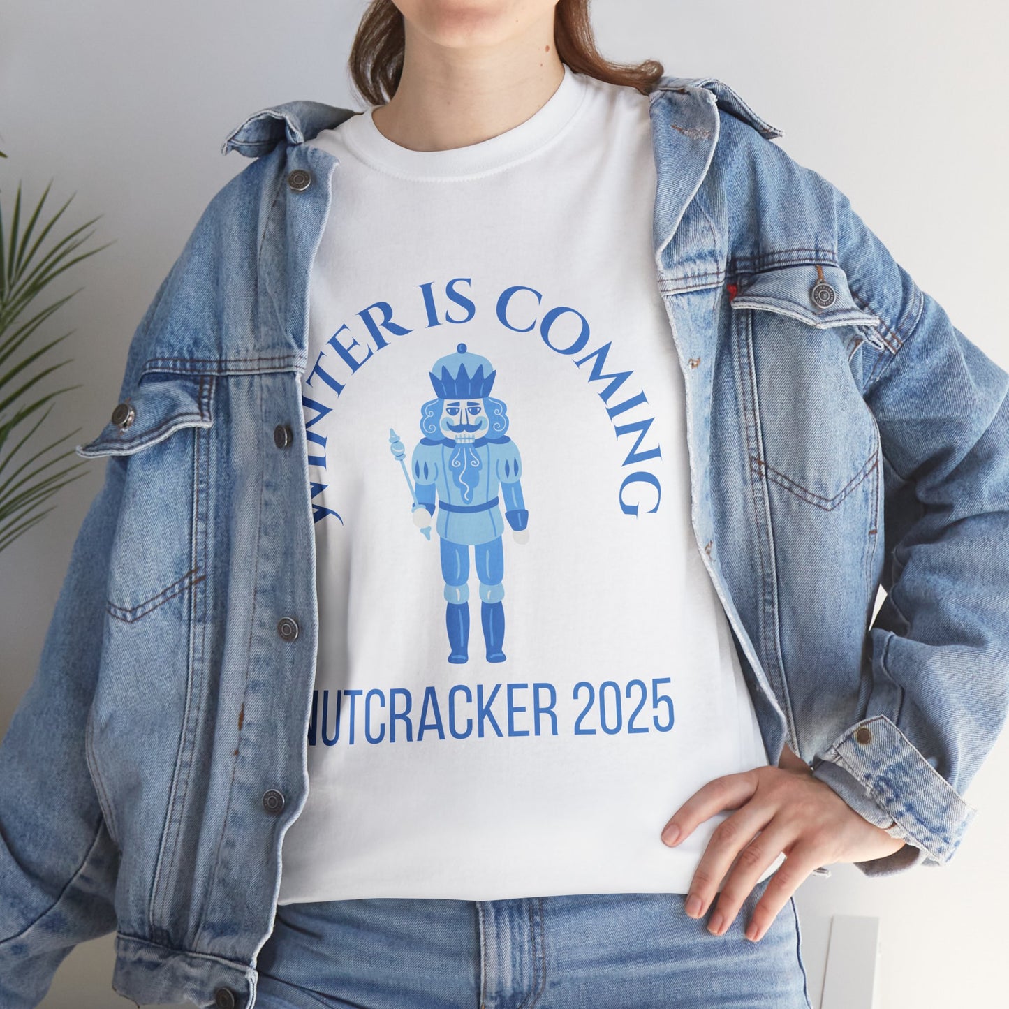Person wearing a white t-shirt with a nutcracker design and text, paired with a denim jacket.
