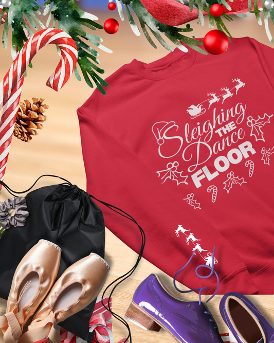 Red shirt with 'Sleighing the Dance Floor' text, surrounded by Christmas decorations and shoes.